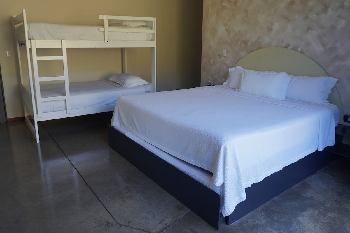 A room with a bunk bed, a single bed, and a nightstand.