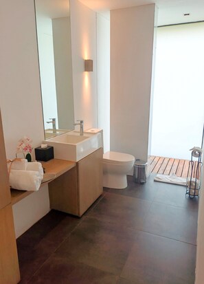 A modern bathroom with a large mirror, a sink, and a toilet.