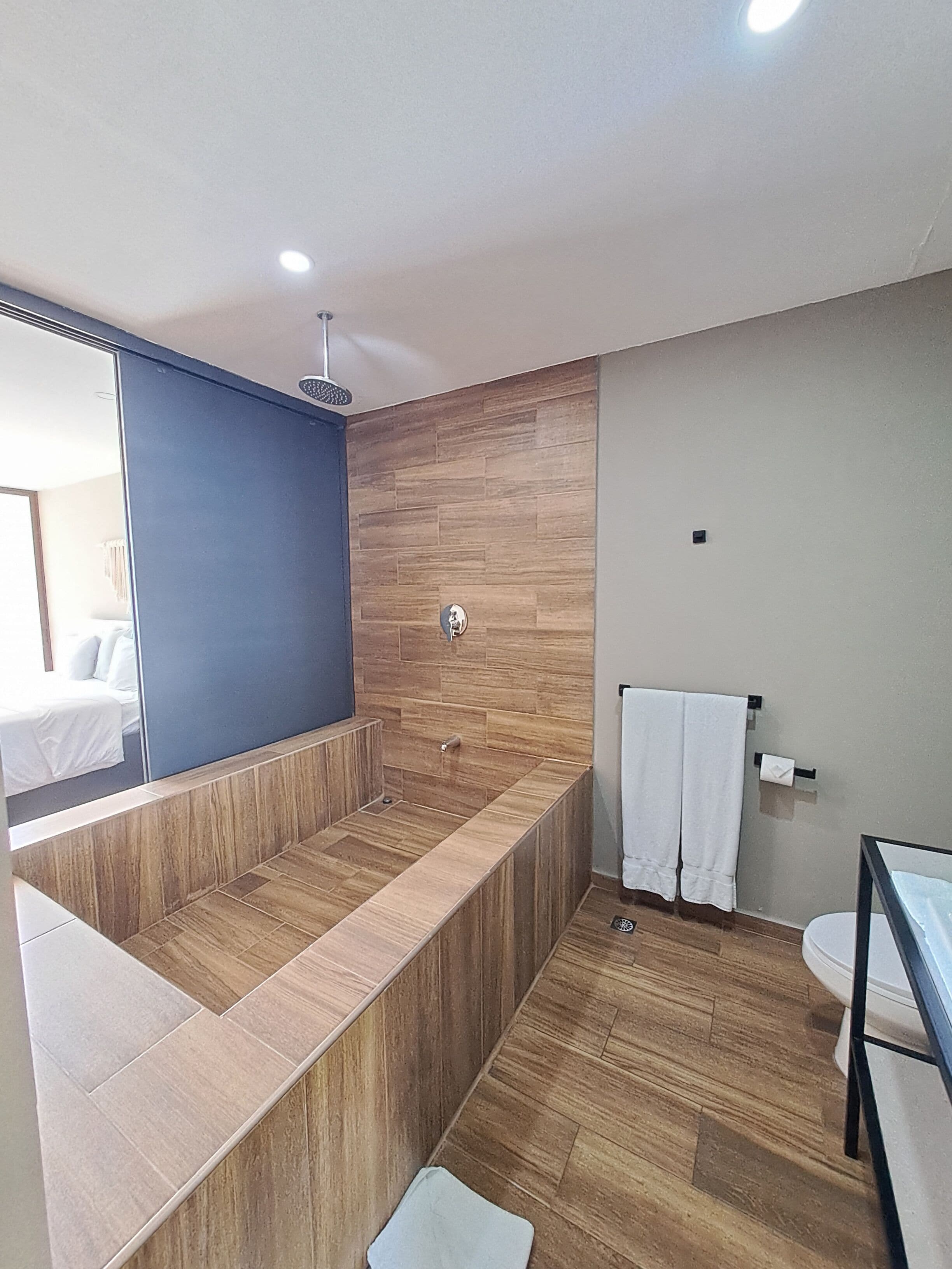 Un baño moderno con tocador de madera, un espejo grande y cabina de ducha separada.