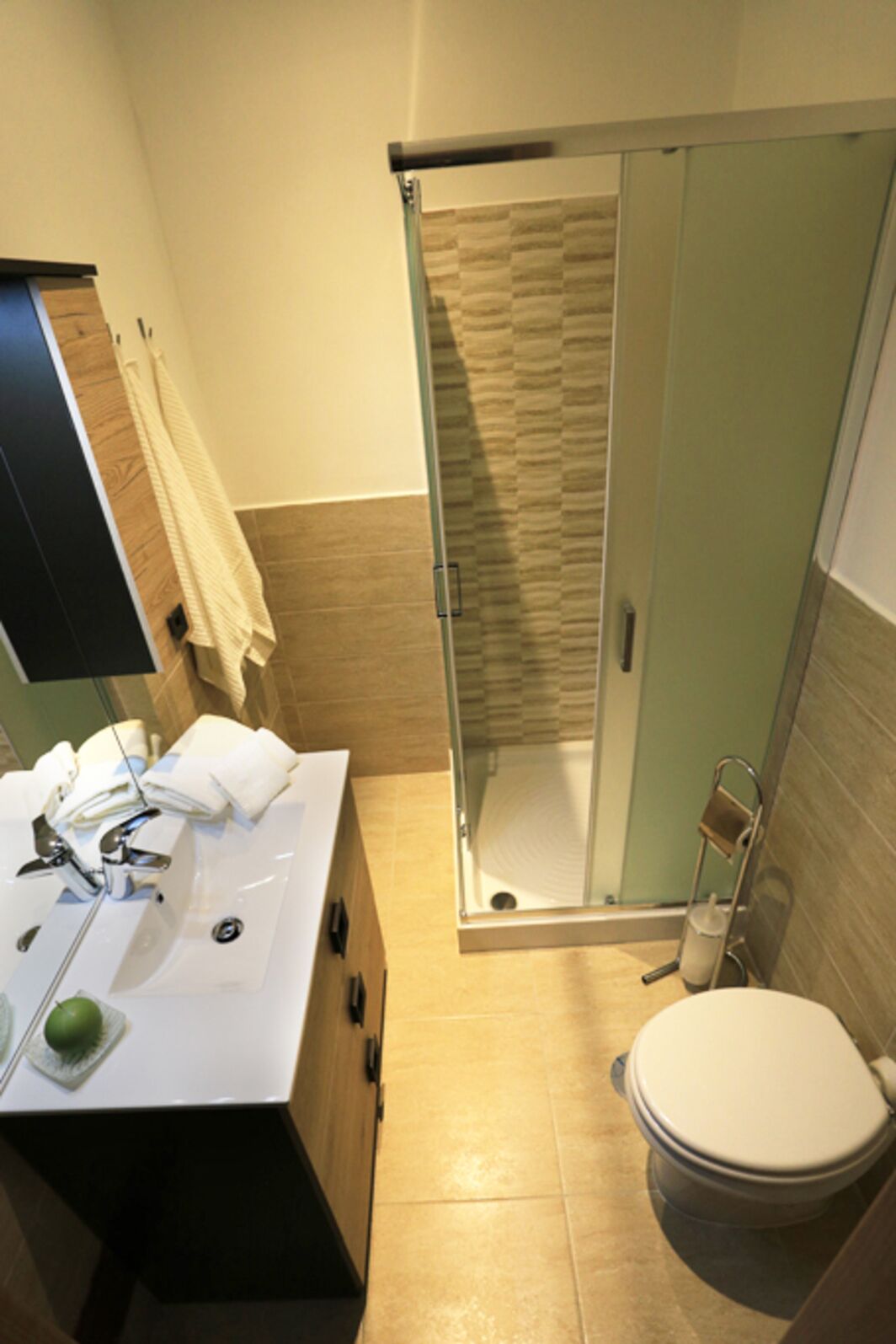 Ein Badezimmer mit einer Duschkabine, einem Waschbecken mit Spiegel und einer Toilette.