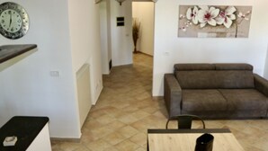 Een woonkamer met een bruine bank, een houten salontafel en een bloemen schilderij aan de muur.
