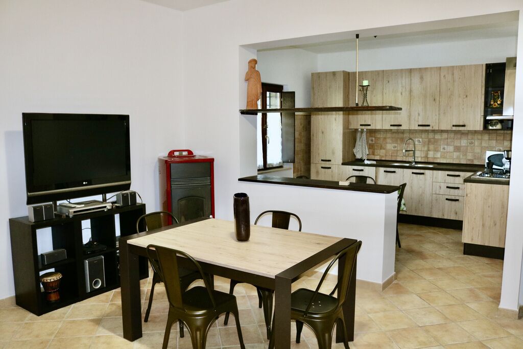 A compact kitchen with a dining area, a TV, and a small statue.