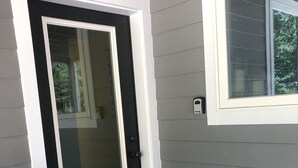 Eine Haustür mit schwarz-weißer Verkleidung, eine Fußmatte mit dem Wort "hello" und ein Fenster mit weißem Rahmen.