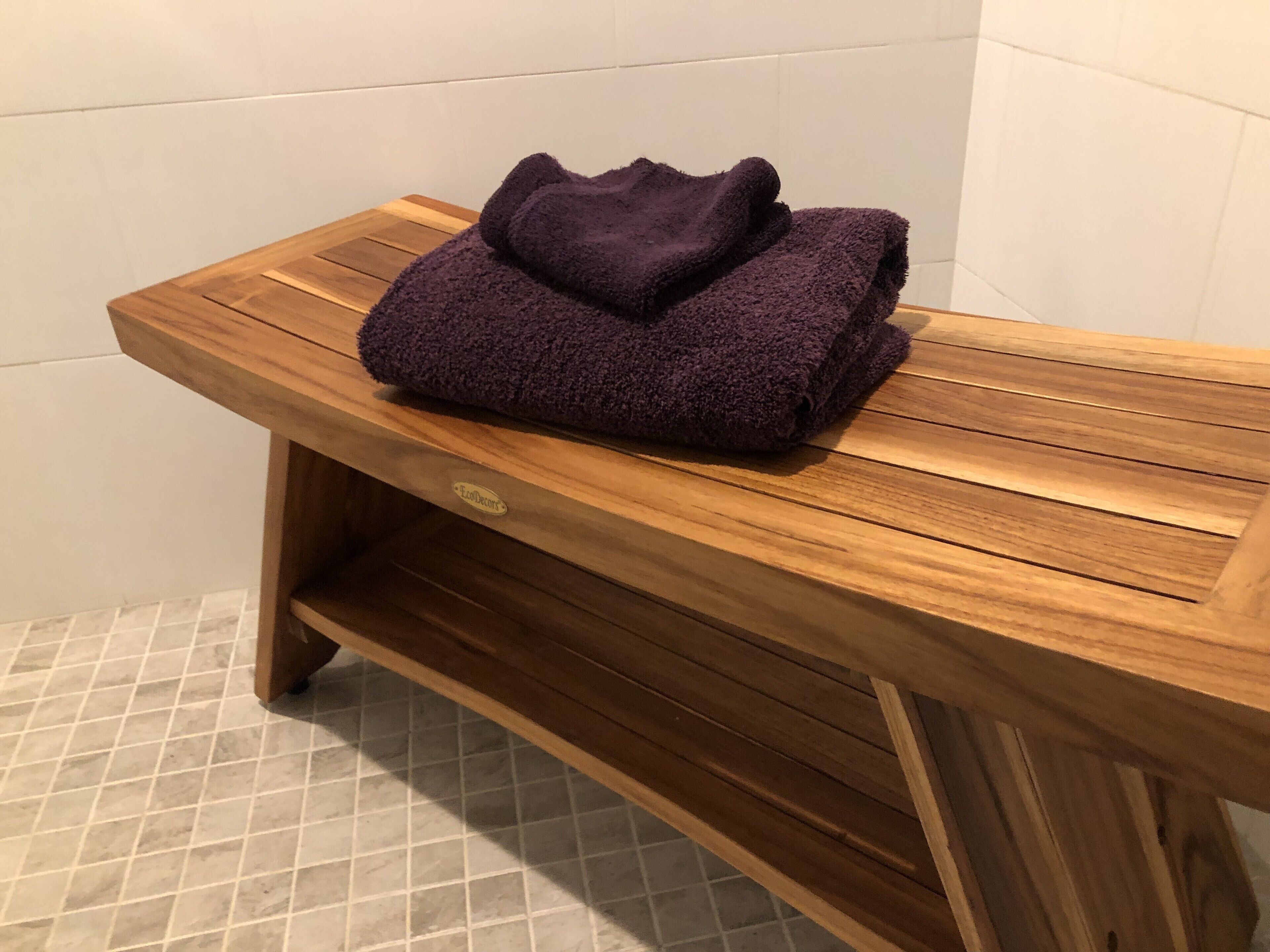 A wooden bench with a folded purple towel on top.