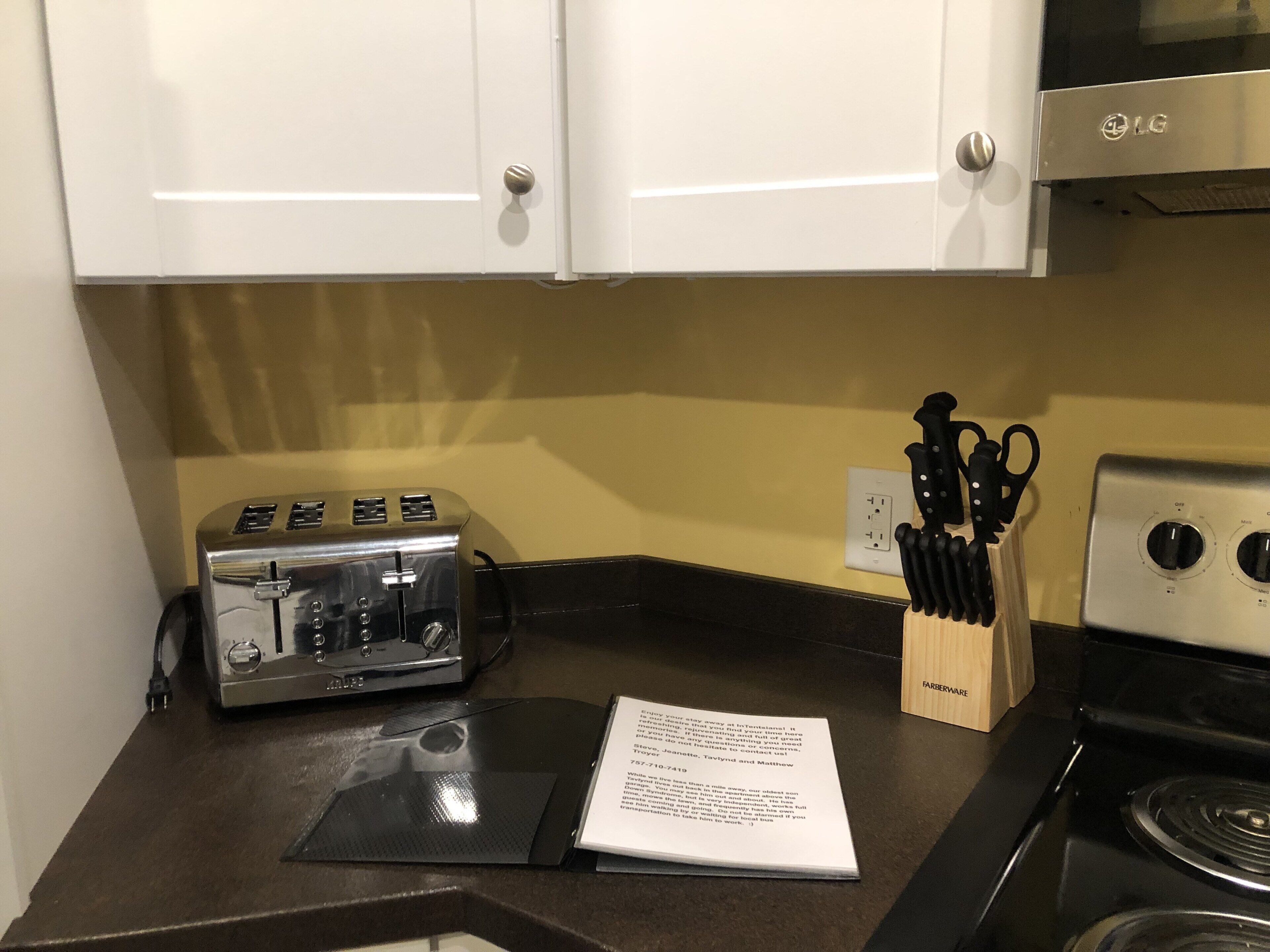 A kitchen with white cabinets, a toaster, a stove, and a knife block.