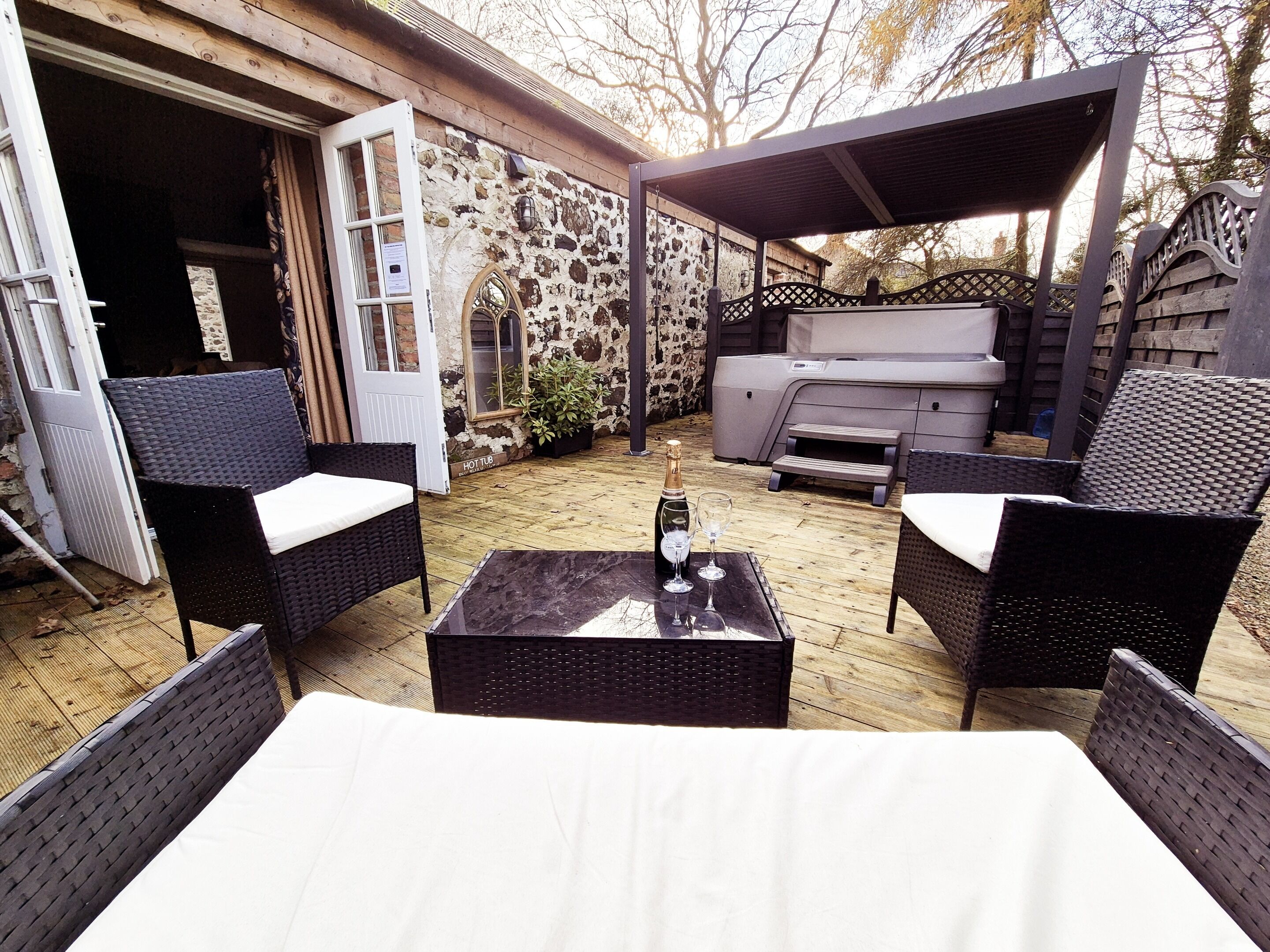 An outdoor patio with wicker furniture, a hot tub, and a barbecue area.