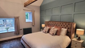 A bedroom with a large bed, a window with curtains, a radiator, and a nightstand with a lamp. - Hawthorn Hollow (Ballymena)