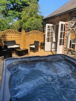 A hot tub with a wooden deck and outdoor furniture, a stone wall, and a wooden fence. - Hawthorn Hollow (Ballymena)