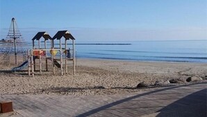 A beach with a wooden boardwalk, a playground, and a clear view of the sea.