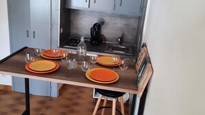 Een compacte keuken met een eettafel voor vier personen, een koffiezetapparaat en kastjes.