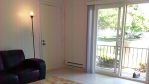 A spacious living room with a sofa, a coffee table, and a large sliding glass door leading to a balcony. - Summer Rental - Great Location - West End Section of Long Branch - Walk to beach (Long Branch)