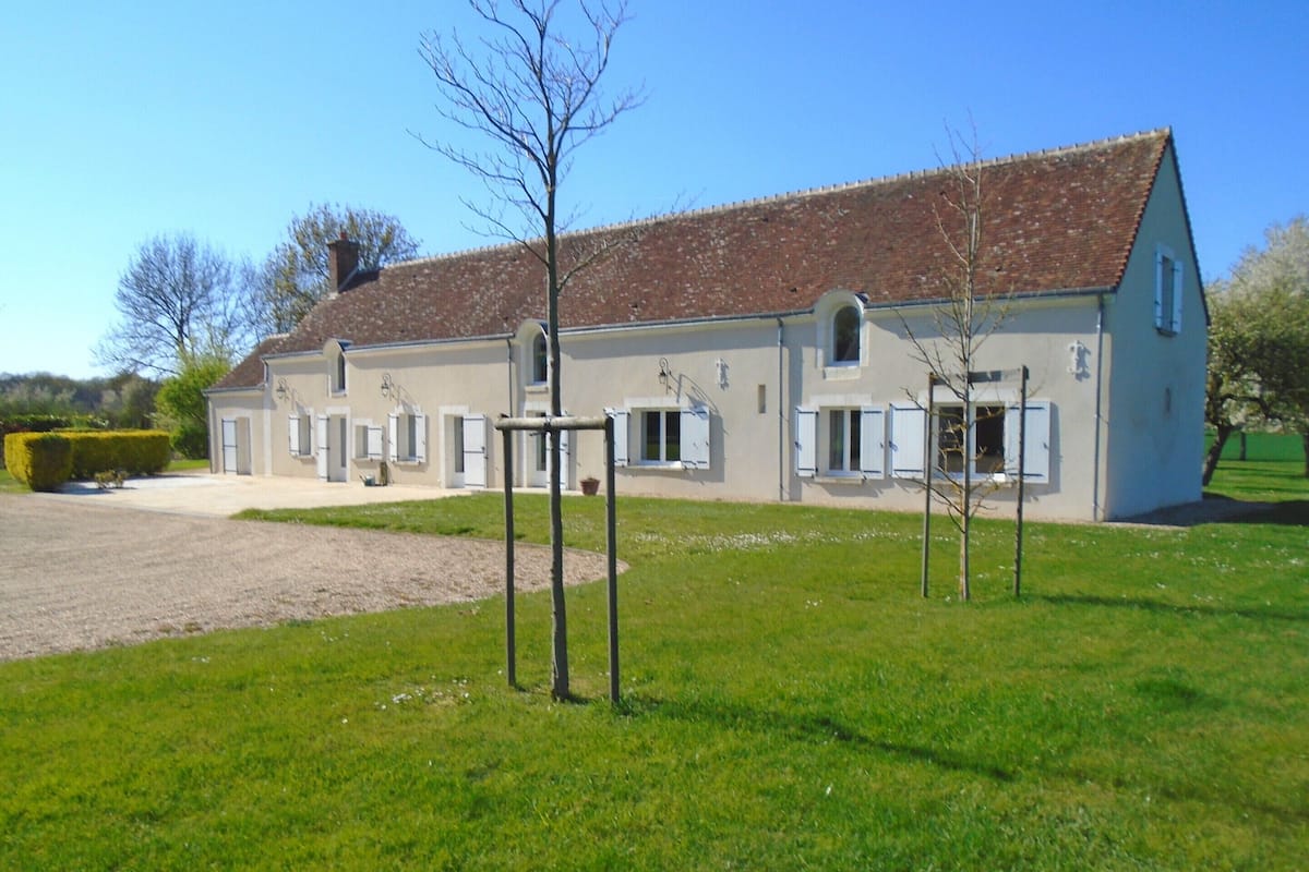A two-story building with a tiled roof, a gravel driveway, and a grassy lawn.