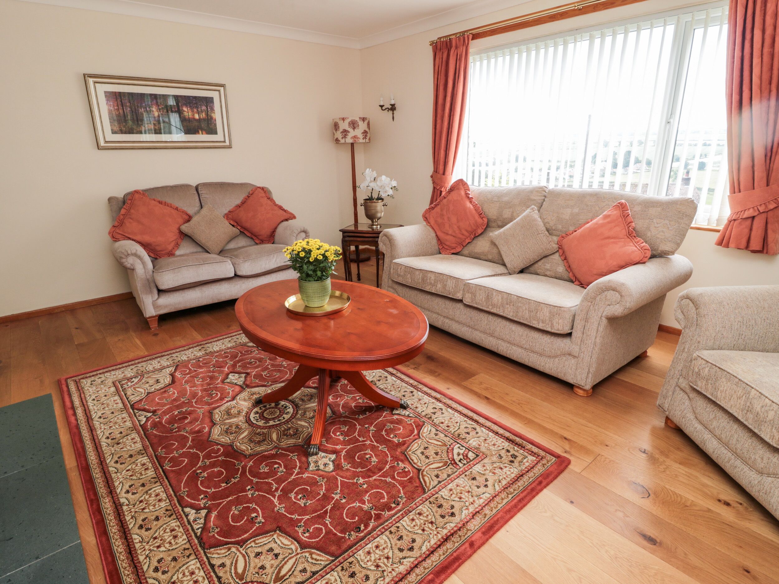 A living room with two sofas, a coffee table, a patterned rug, a framed picture on the wall, and a window with curtains.