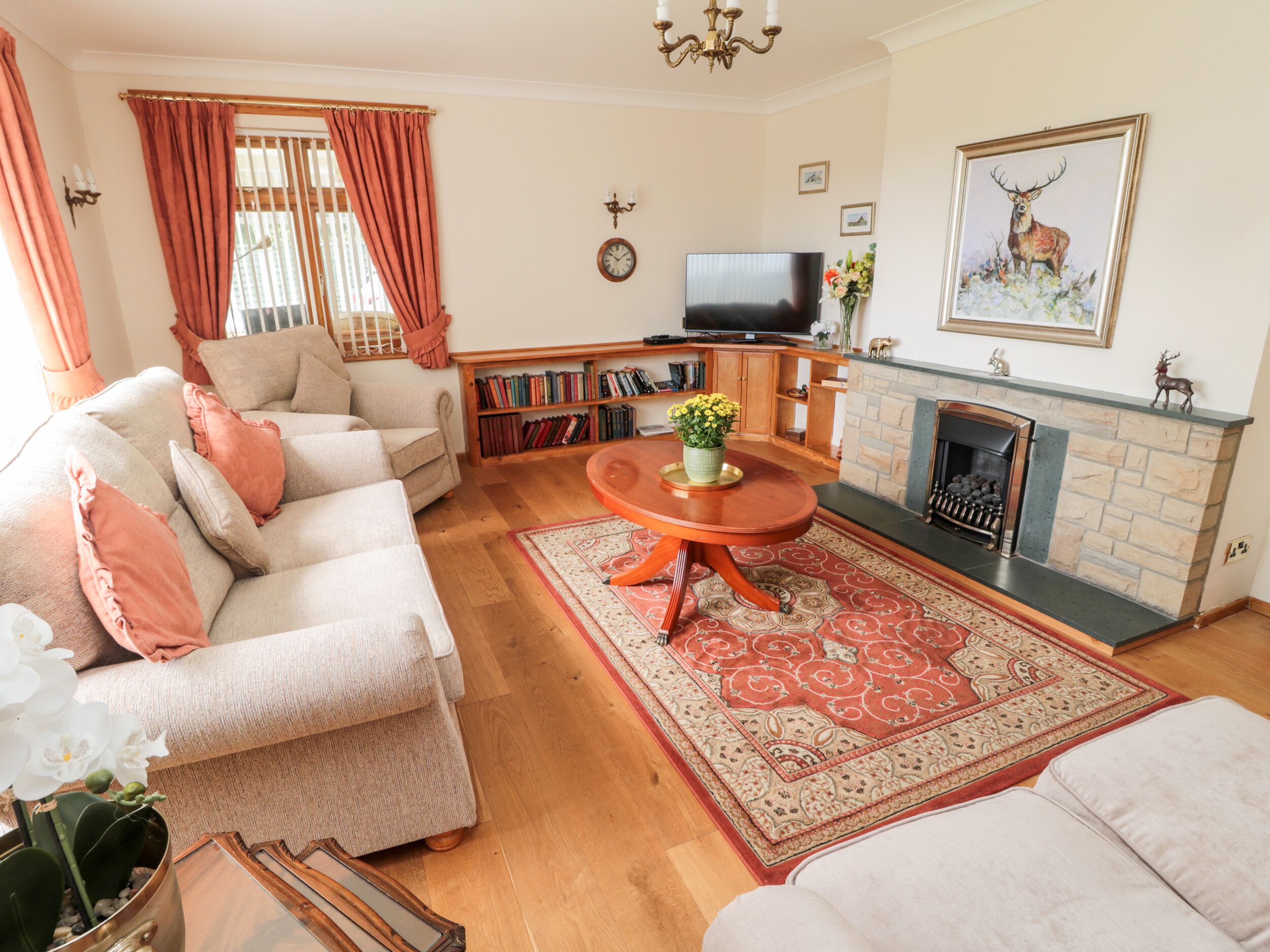 A living room with a sofa, a coffee table, a fireplace, a television, and a bookshelf.