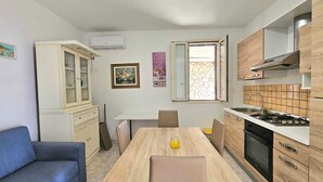 A compact kitchen with a dining table, chairs, a sofa, and a stove.