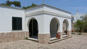 A building with a white exterior, stone base, and three arched doorways.