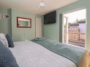 Un dormitorio con cama, espejo, televisión y vistas al exterior.