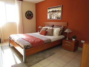 Cozy retreat with a comfortable bed, sheer curtains, and a framed picture.
