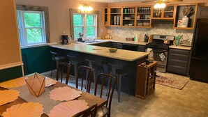 A kitchen with a central island, bar stools, a dining table with decorative placemats, and a built-in oven.