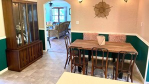 A dining area with a wooden table and chairs, a cabinet with glass doors, and a wall-mounted decorative piece.