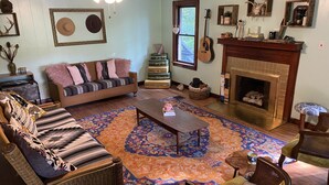 A cozy living room with a sofa, chairs, a coffee table, a fireplace, and a guitar.