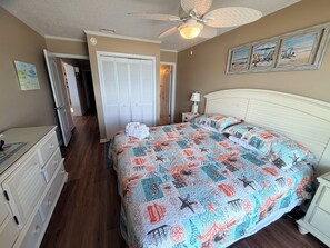 A bedroom with a bed, a nightstand, a dresser, a ceiling fan, and a door leading to another room. - Oceanfront 3 BR 2.5 bath Tilgham Beach & Racquet Club # 307. 2 pools, Tennis (North Myrtle Beach)