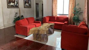 Un saló modern amb sofàs vermells, una taula baixa de fusta i dos quadres de cavalls.