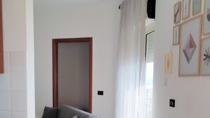 A modern living room with a grey sofa, a wooden dining table, and a glass vase. - Window to the Sea by Alexander 2p (Balestrate)