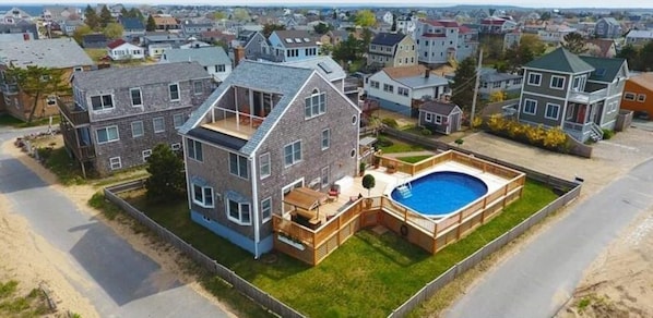 Une maison à deux étages avec une piscine, une terrasse et une cour clôturée.
