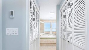 Un couloir avec des placards blancs, un interrupteur et une fenêtre donnant sur une salle de bain.
