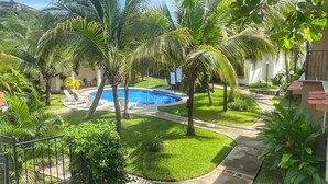 Una piscina rodeada de palmeras y un césped bien cuidado.