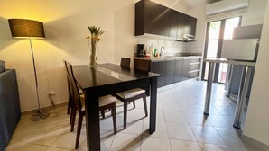 Una cocina moderna con armarios oscuros, una mesa de comedor y una lámpara.