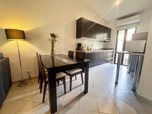 A modern kitchen with dark cabinets, a dining table, and a lamp.