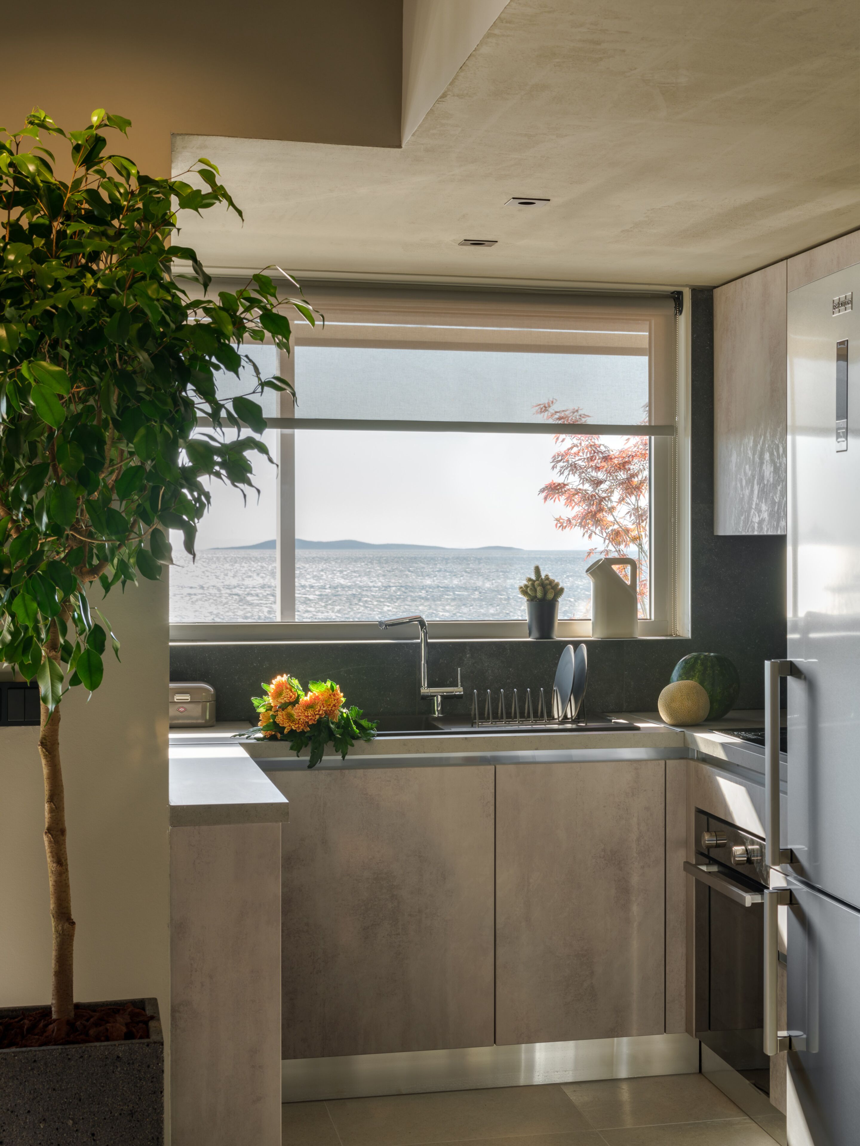A modern kitchen with a large window, a sink, and a refrigerator.