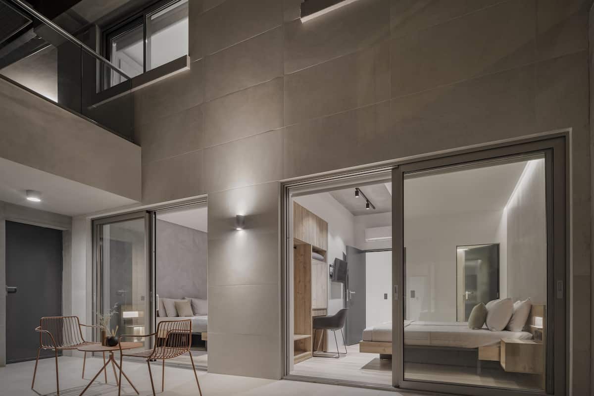 Un intérieur moderne comprenant un vaste espace de vie, un ensemble de salle à manger et une chambre dotée d’une grande porte-fenêtre coulissante.