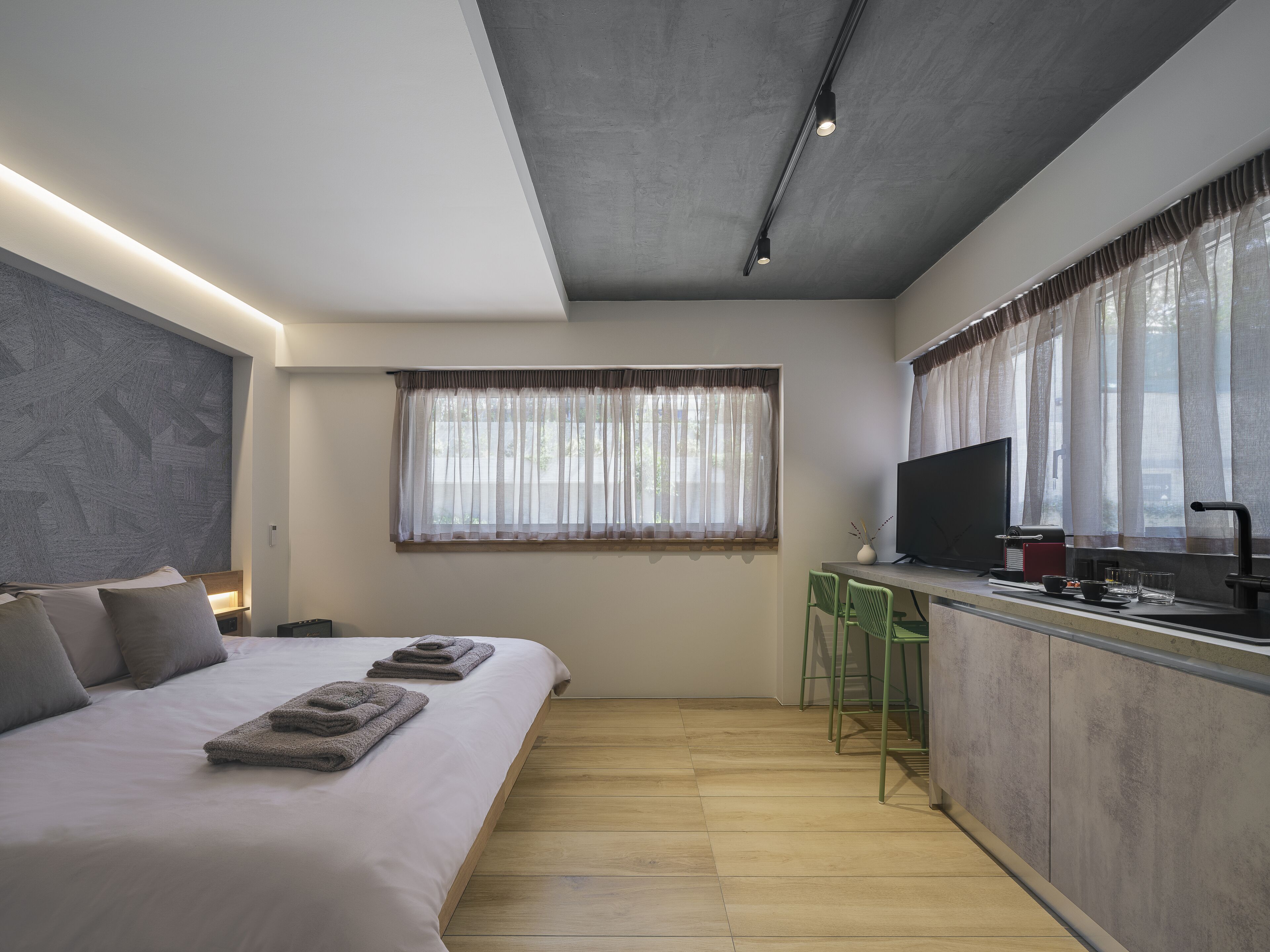 Una camera d'albergo moderna con un letto grande, angolo cottura e televisore.