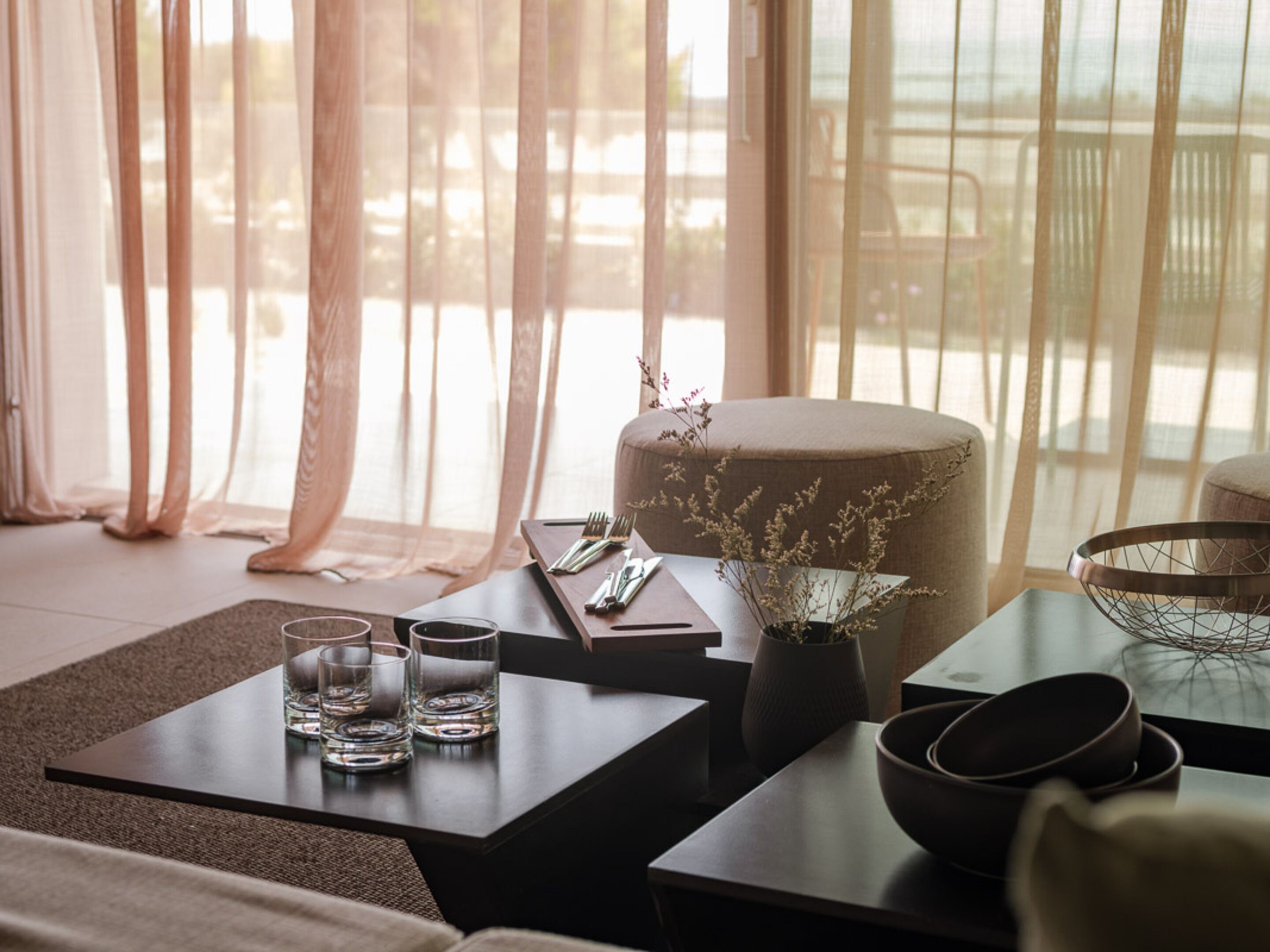 A modern room with a sofa, a coffee table, and a dining table set with glasses and cutlery.