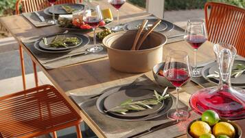 A dining table set with plates, cutlery, glasses, and a bowl of fruit.