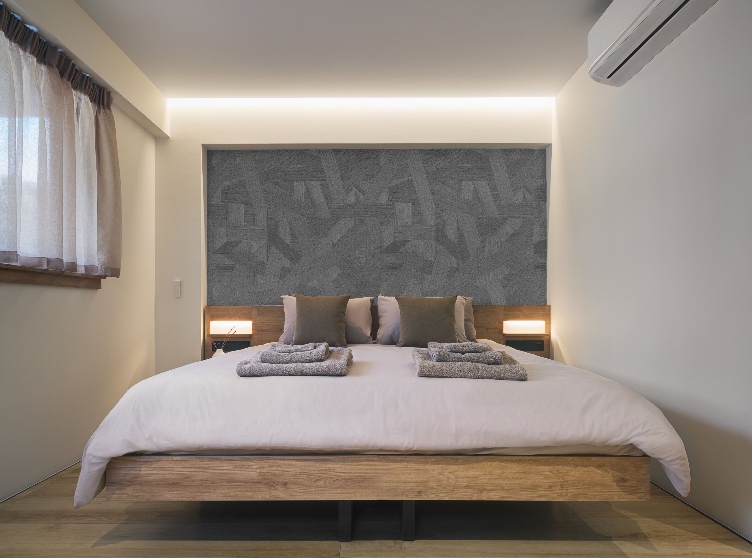A modern hotel room with a large bed, wooden headboard, and two bedside lamps.