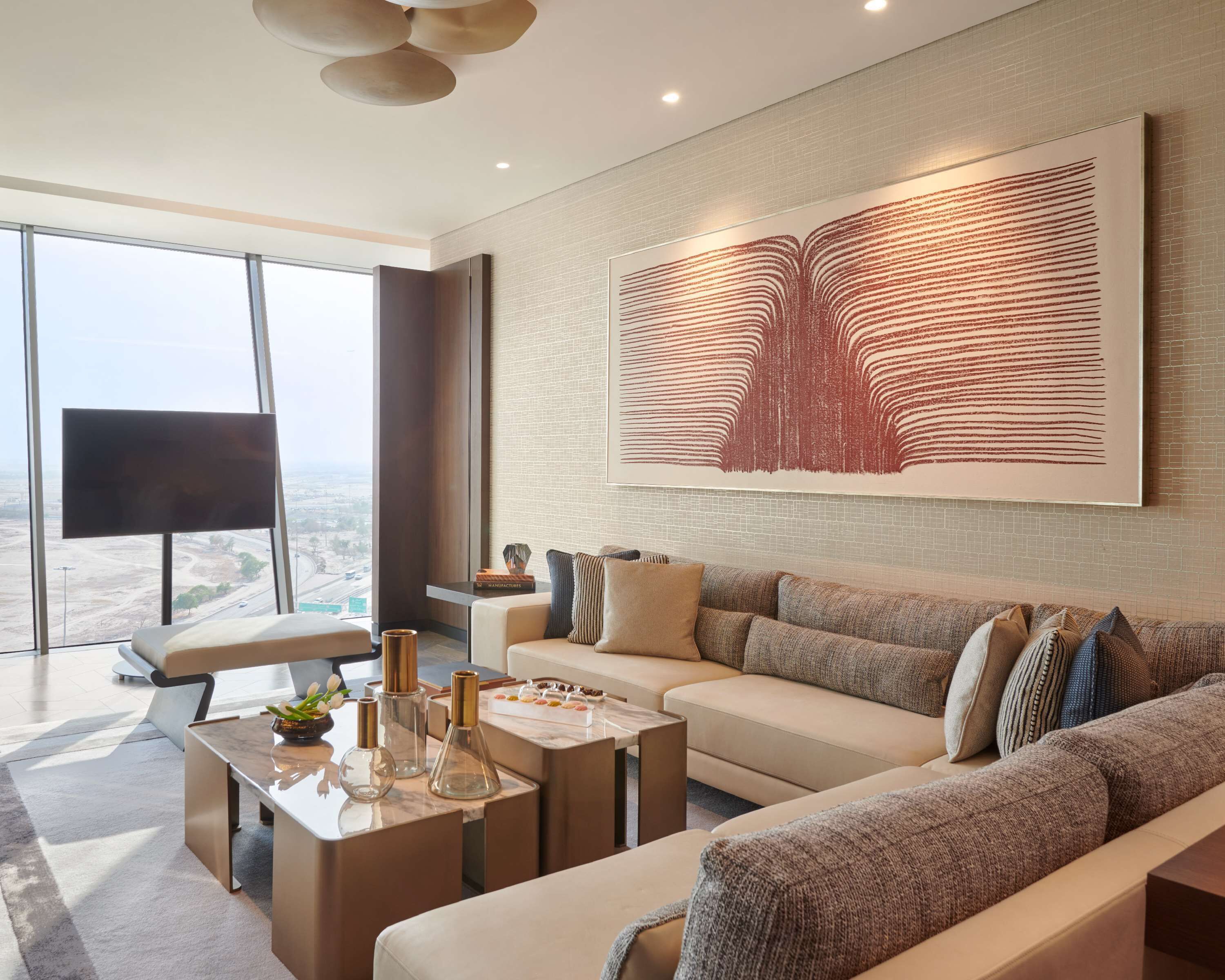 Una sala de estar moderna con un ventanal grande, un conjunto de sofás, una mesa de centro y un cuadro abstracto de gran tamaño en la pared.