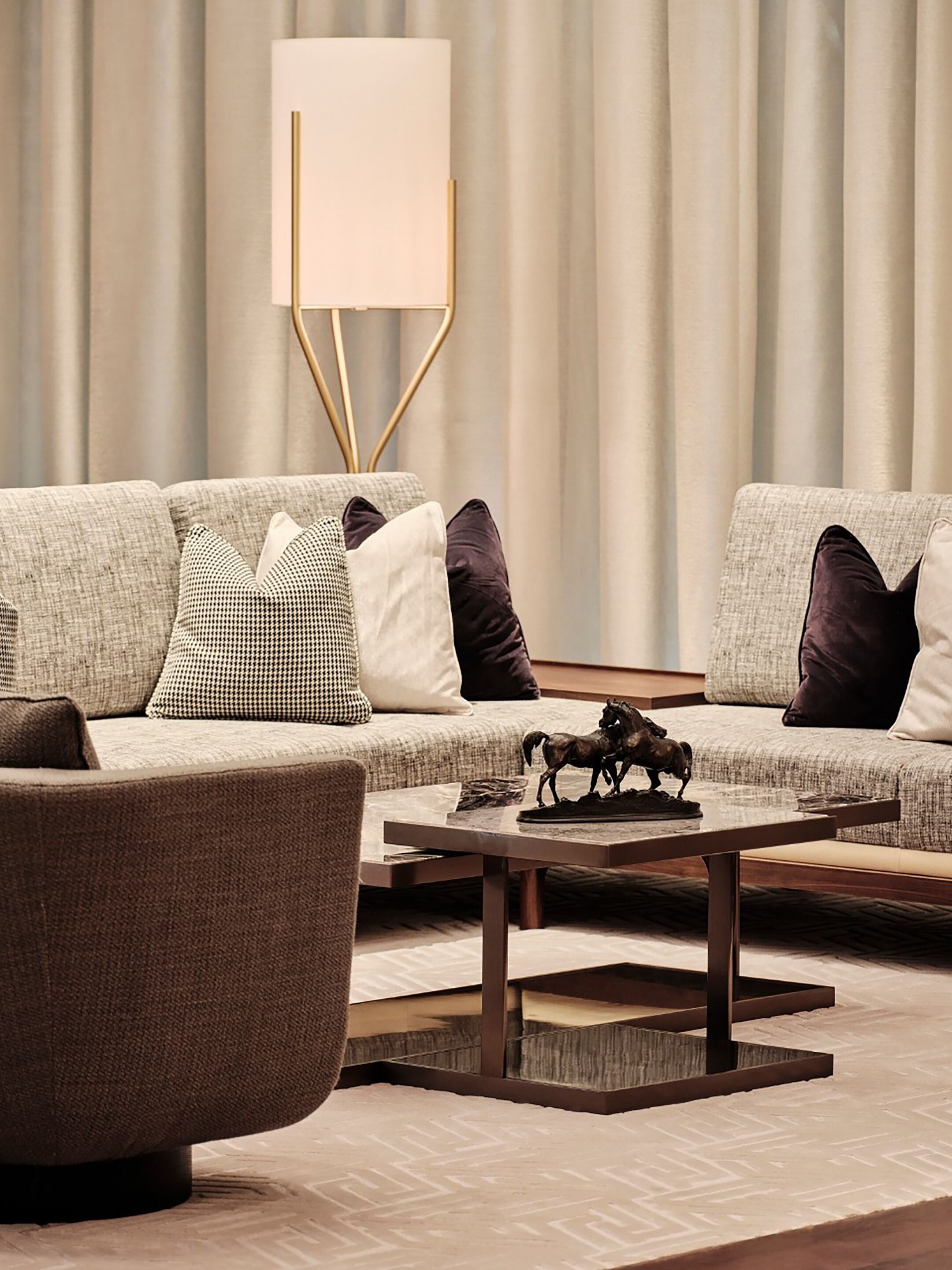 Ein modernes Wohnzimmer mit einem grauen Sofa, einem braunen Sessel und einem Couchtisch mit einer Pferdestatue.