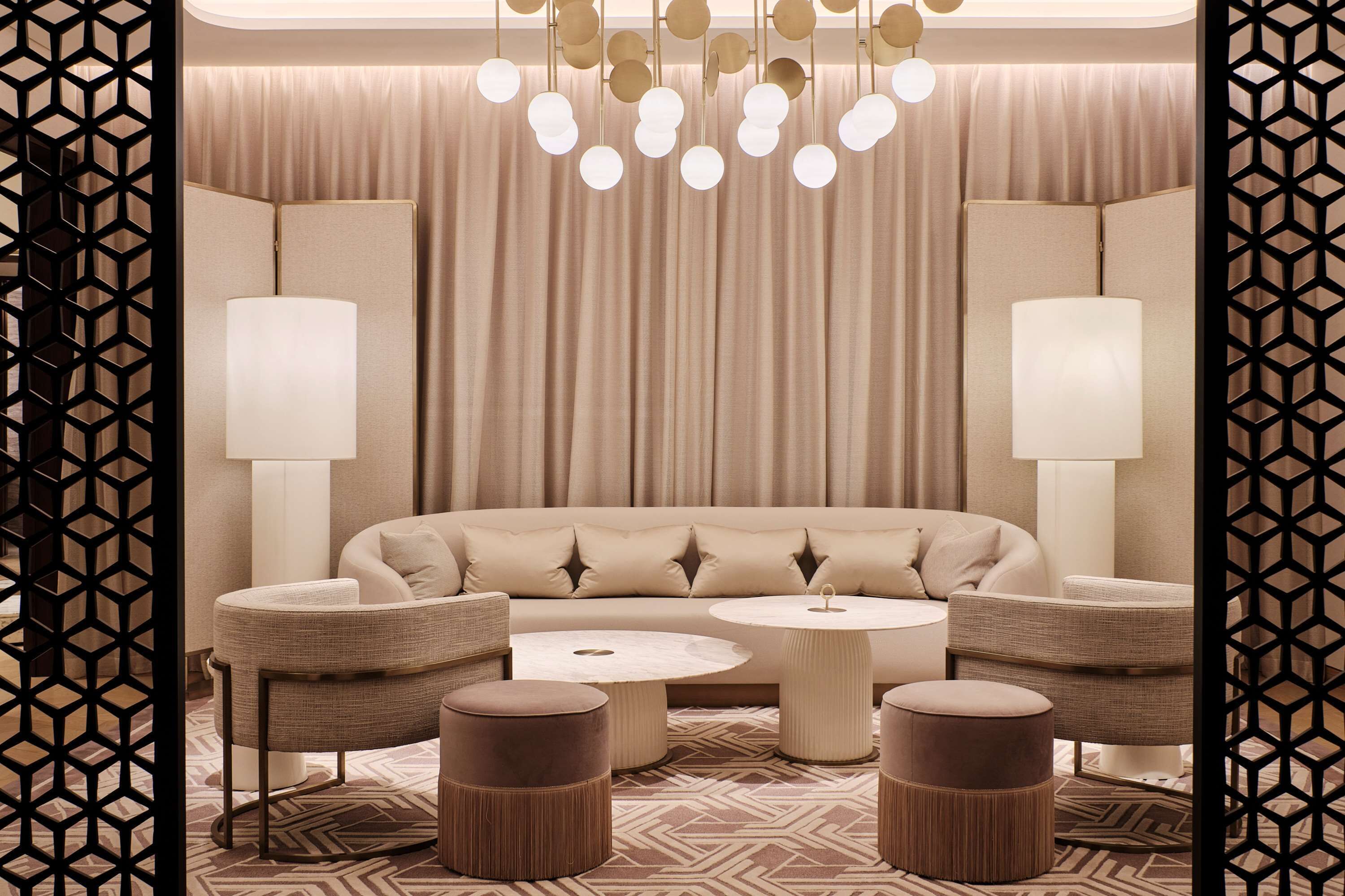 A modern living room with a sectional sofa, two armchairs, a coffee table, and a patterned rug.