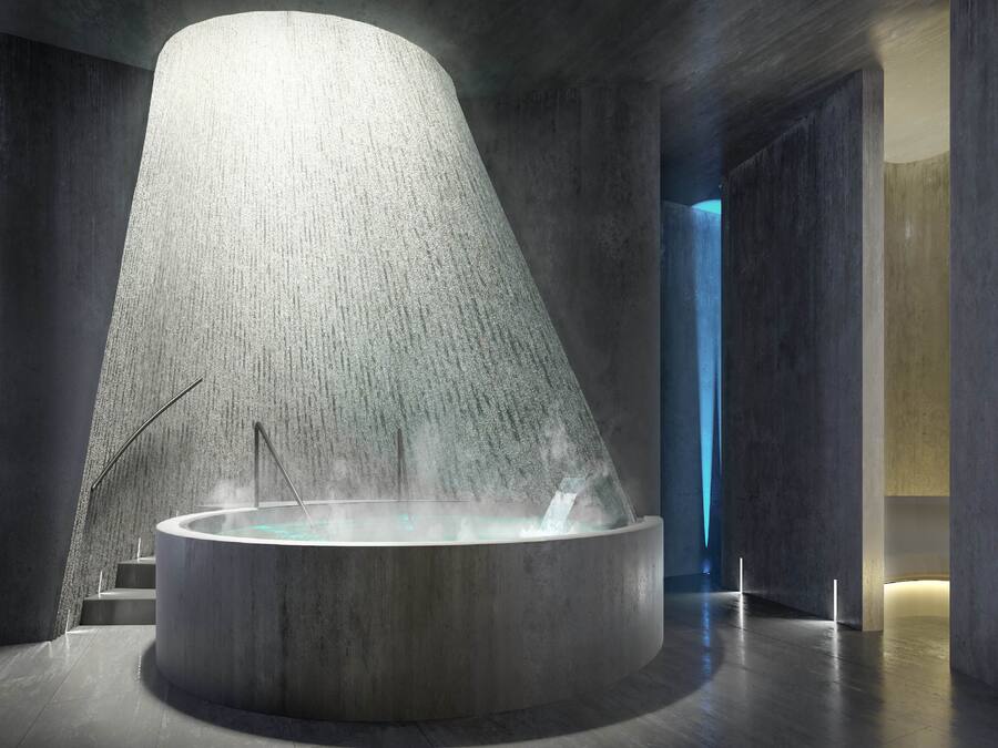 A modern spa area with a large, circular hot tub and a textured wall.