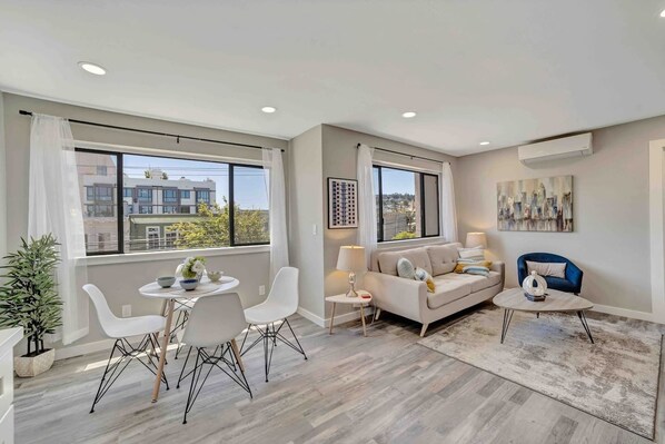 Relax in this stylish living room with a city view, featuring a sofa, coffee table, and dining area.