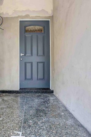 A simple door with a decorative element above the handle, set within a plain wall.