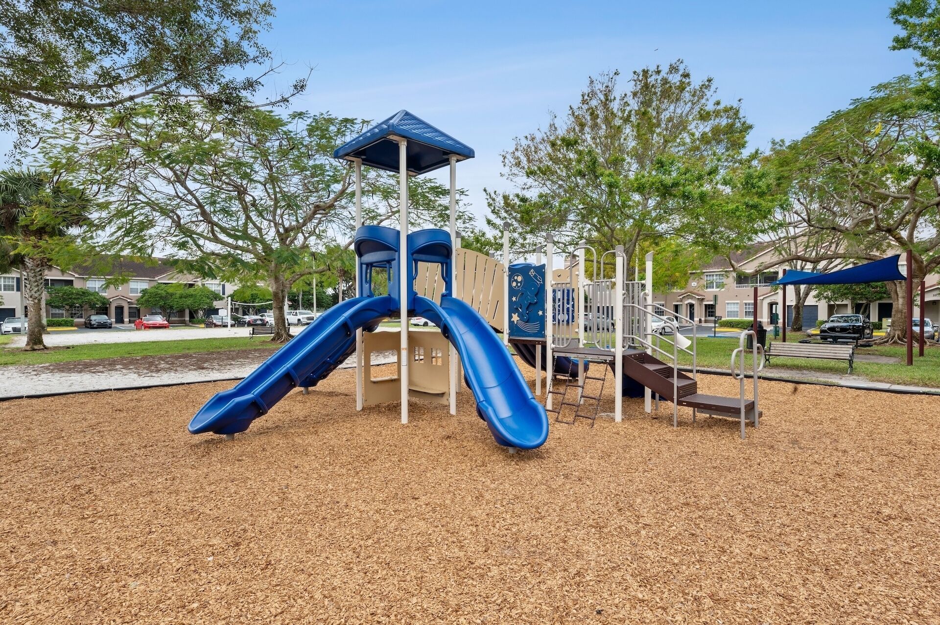 A playground with two blue slides and a climbing structure.