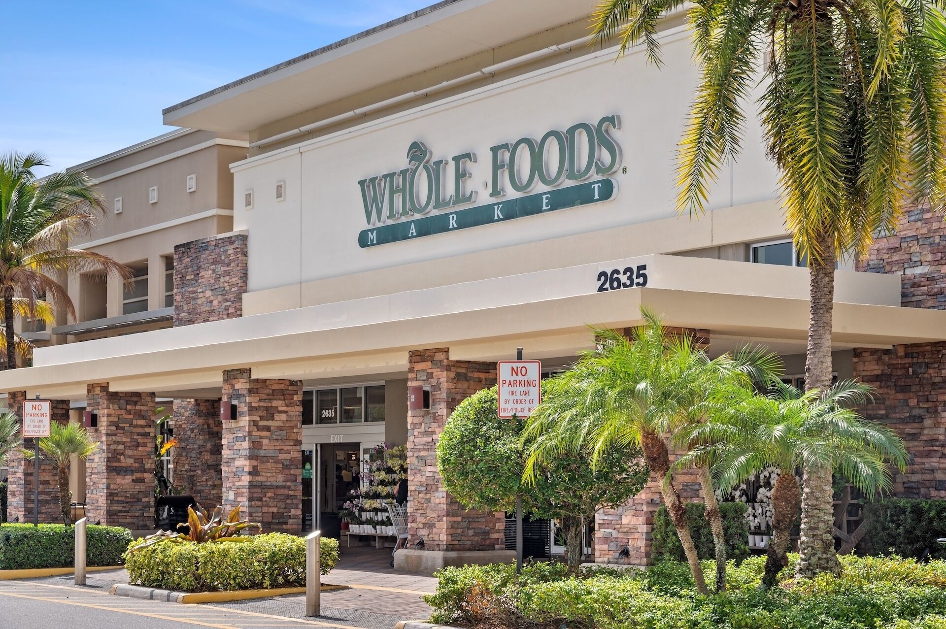 A Whole Foods store with a brick facade, numbered 2635, and a 'No Parking' sign indicating a fire lane.