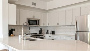 Una cocina moderna con armarios blancos, electrodomésticos de acero inoxidable y una isla central.