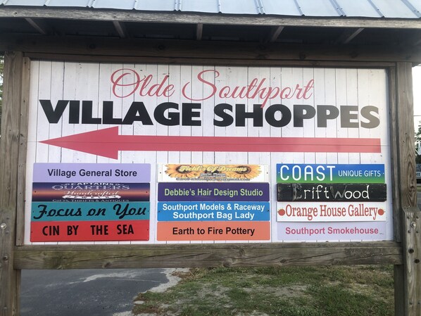 Un letrero para las tiendas del Olde Southport Village con varios nombres de negocios.