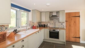 A modern kitchen with white cabinets, a wooden countertop, a Bosch oven, and a patterned backsplash.